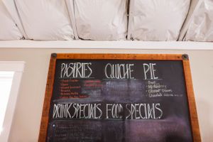 Chalkboard menu displaying pastries, quiche, and daily specials in white lettering.