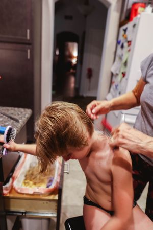 Person getting their hair styled in a dimly lit room with bathroom fixtures visible.