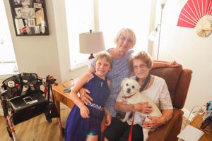 Family gathering in a bright living room with a small white dog.