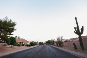 Panoramic view of a suburban neighborhood street with desert landscaping at sunset.