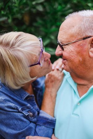 Close-up shot of a senior couple's intimate moment in an outdoor garden setting.