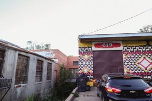Colorful geometric patterns and murals decorate the exterior walls of urban buildings along a street.