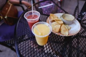 Drinks and chips served on a black metal patio table outdoors.