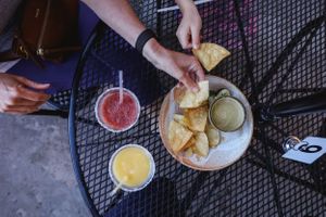Colorful drinks and appetizers served on a black metal patio table.