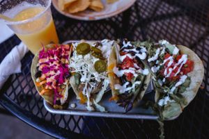 Mexican street tacos topped with colorful garnishes and sauces on a plate.