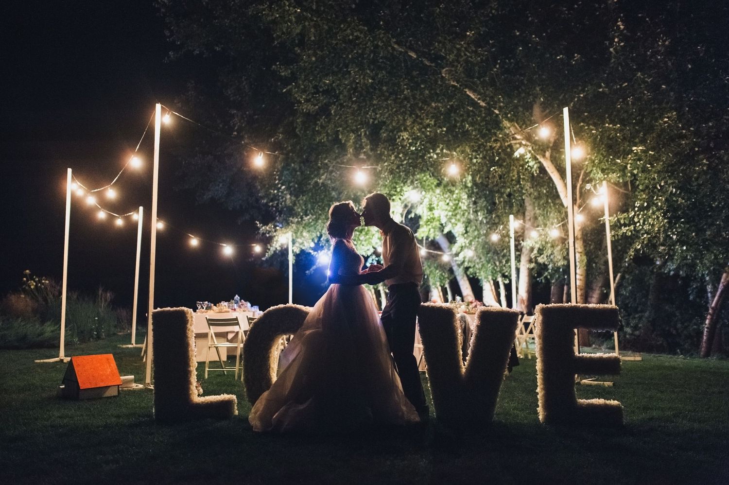 Bride and groom kiss in front of a love sign