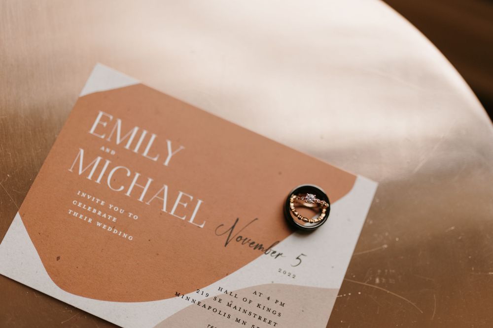 Close-up of a wedding invitation for Emily and Michael with a rose gold ring box.