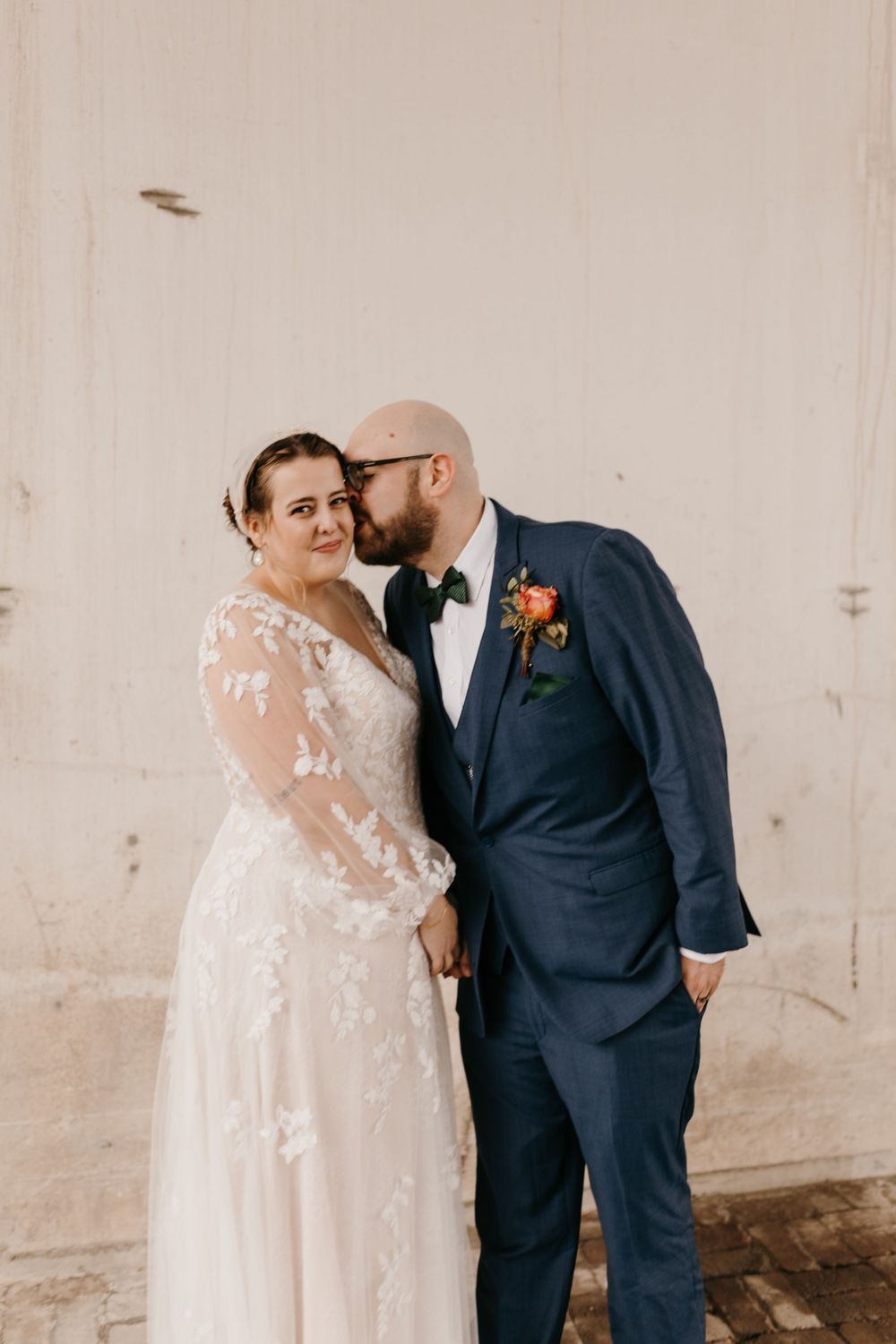 Bride and groom sharing tender moment, groom kissing bride's cheek in wedding attire.