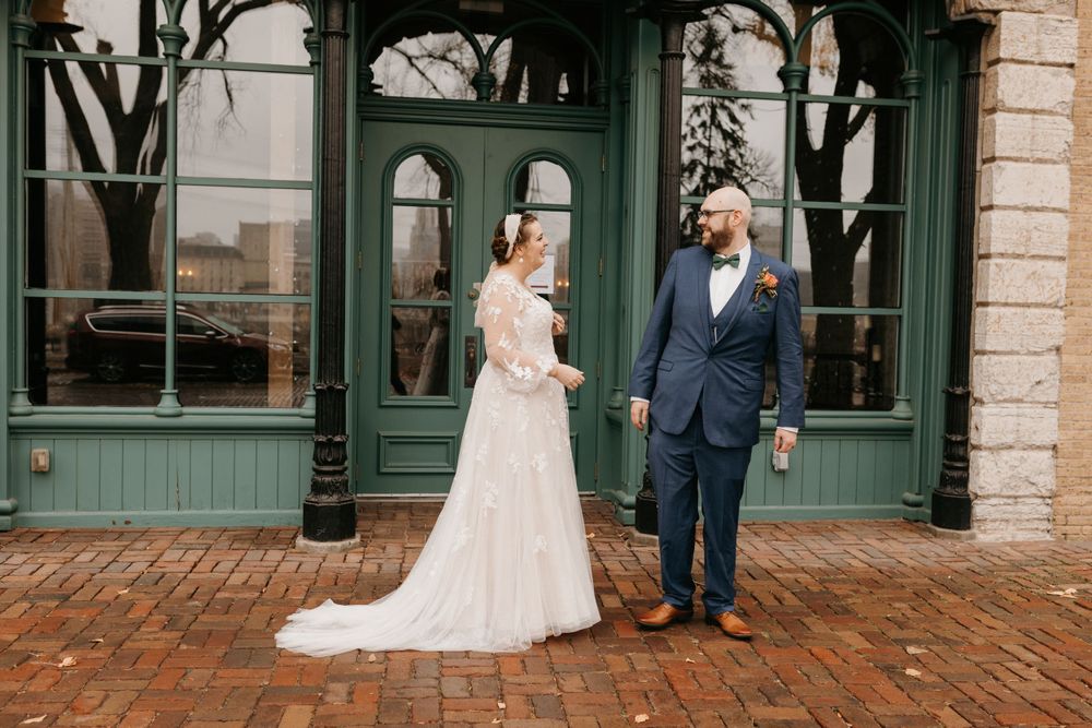 Wedding couple sharing first look moment outside charming green vintage storefront.