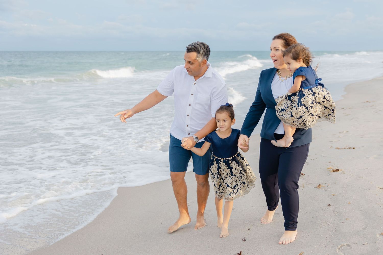 Mom and dad walking with daughters on the beach looking at ocean. Space Coast FL Photographer