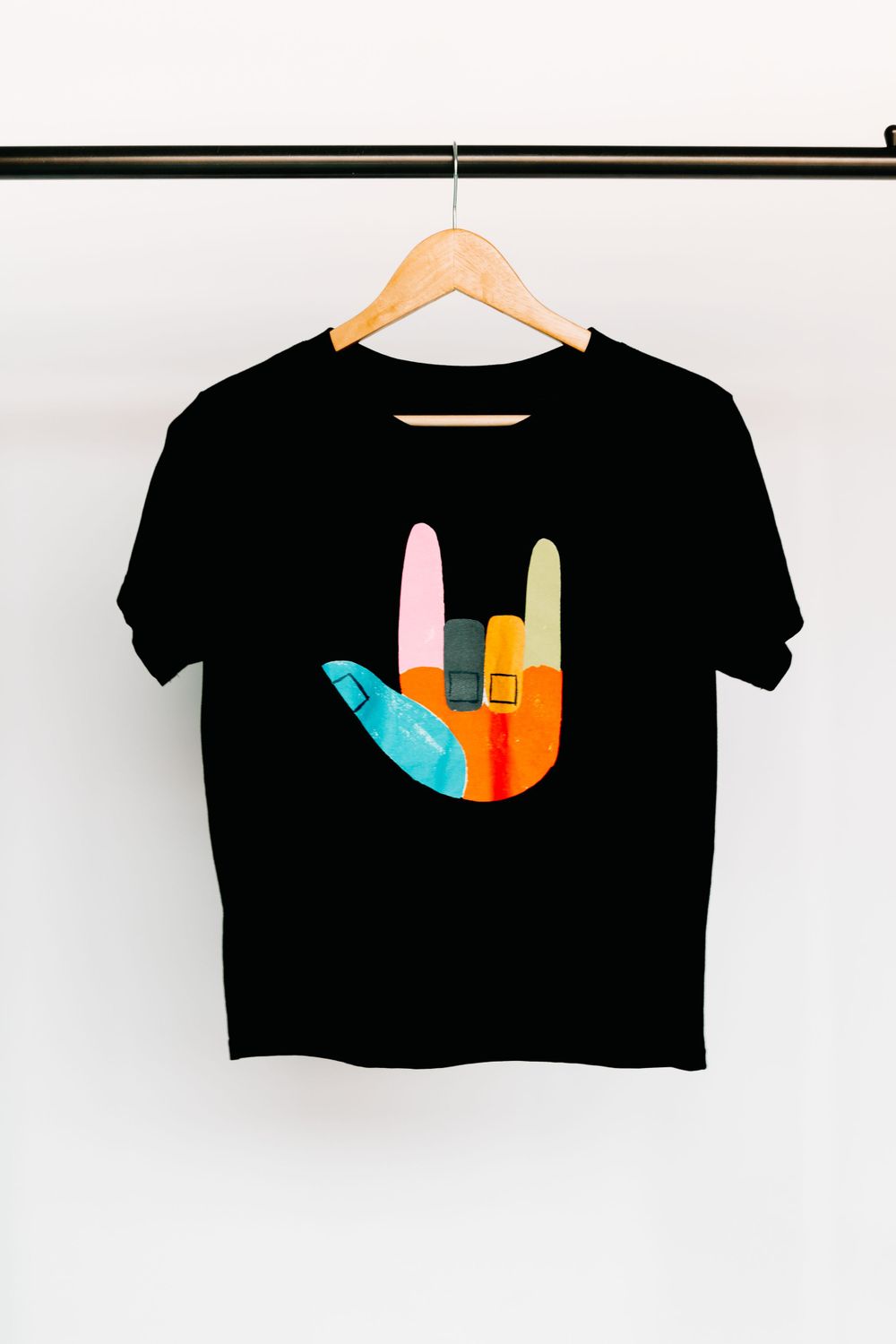Black crop top t-shirts with colorful geometric designs displayed on hangers.