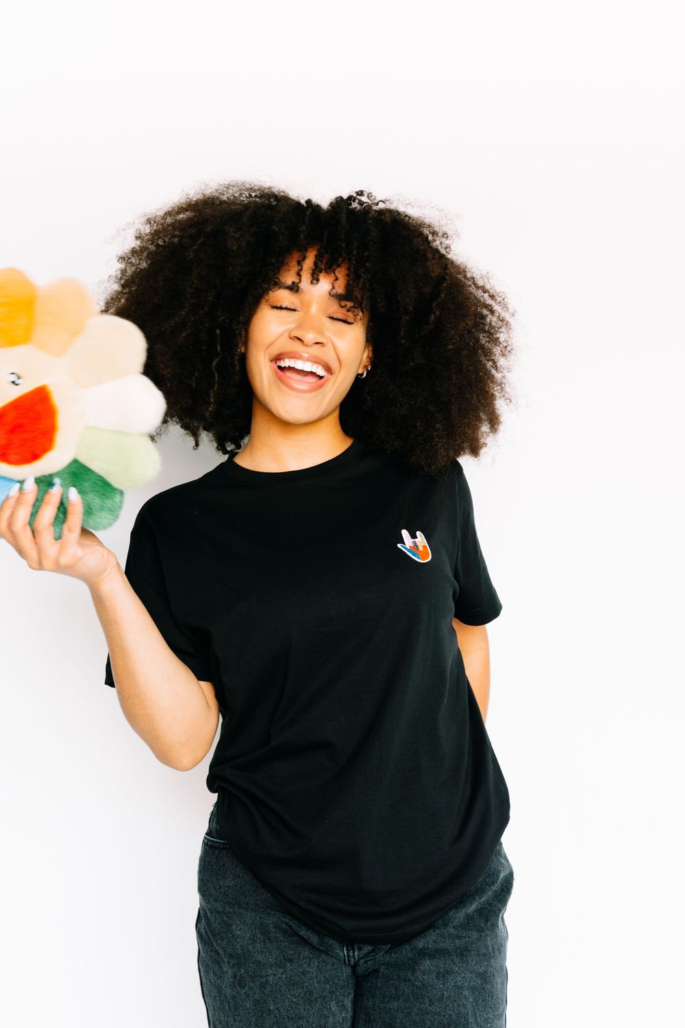 Person in black t-shirt holding colorful decorative items against white background.
