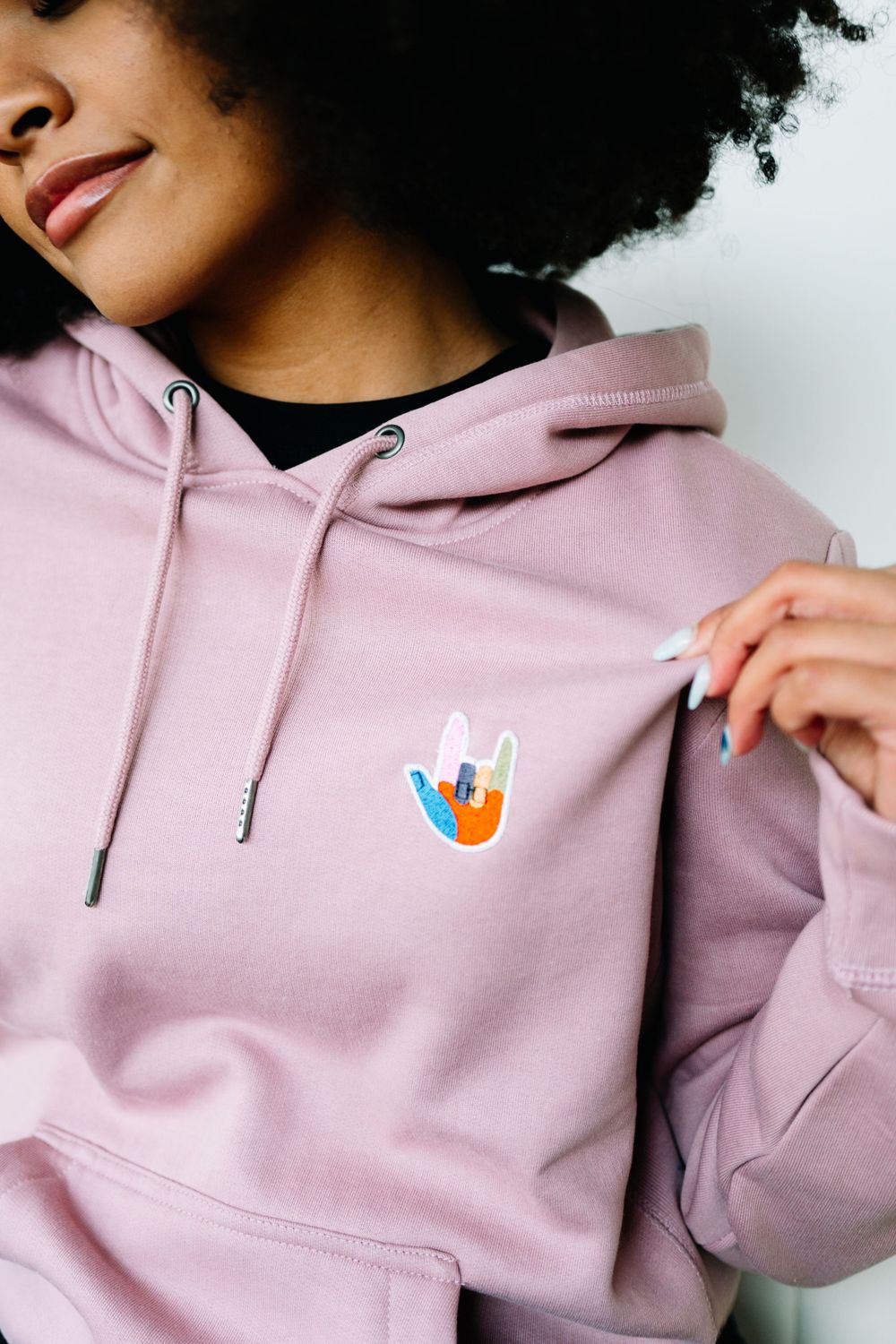 Close-up shots of pink hoodie with small colorful pin detail.