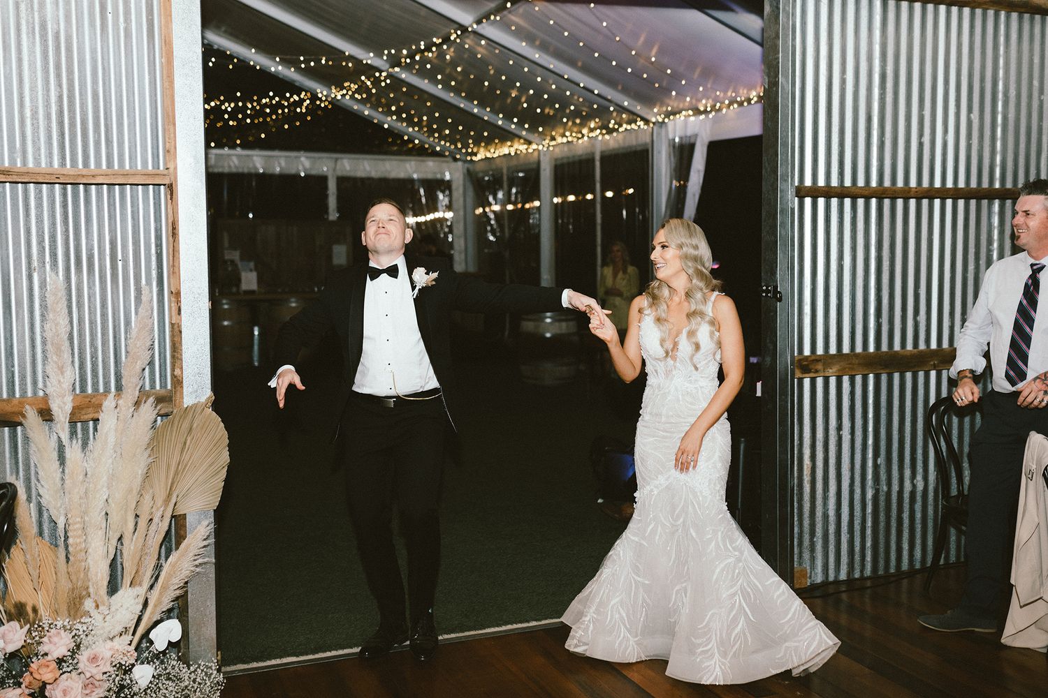 Wedding celebration in a rustic venue with string lights and dancing guests.