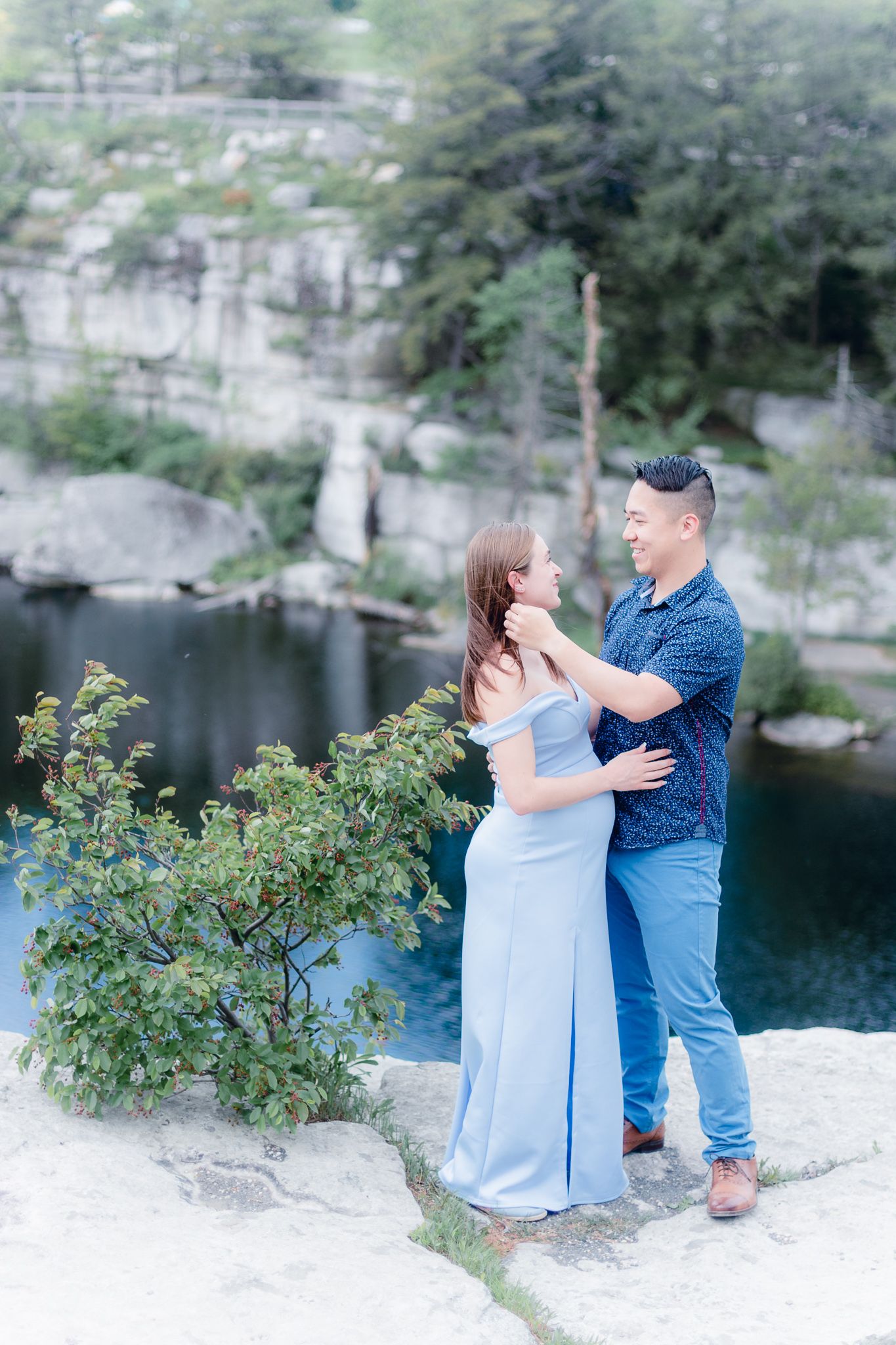 couple on a cliff overlooking a lake posing for a maternity and engagement photo