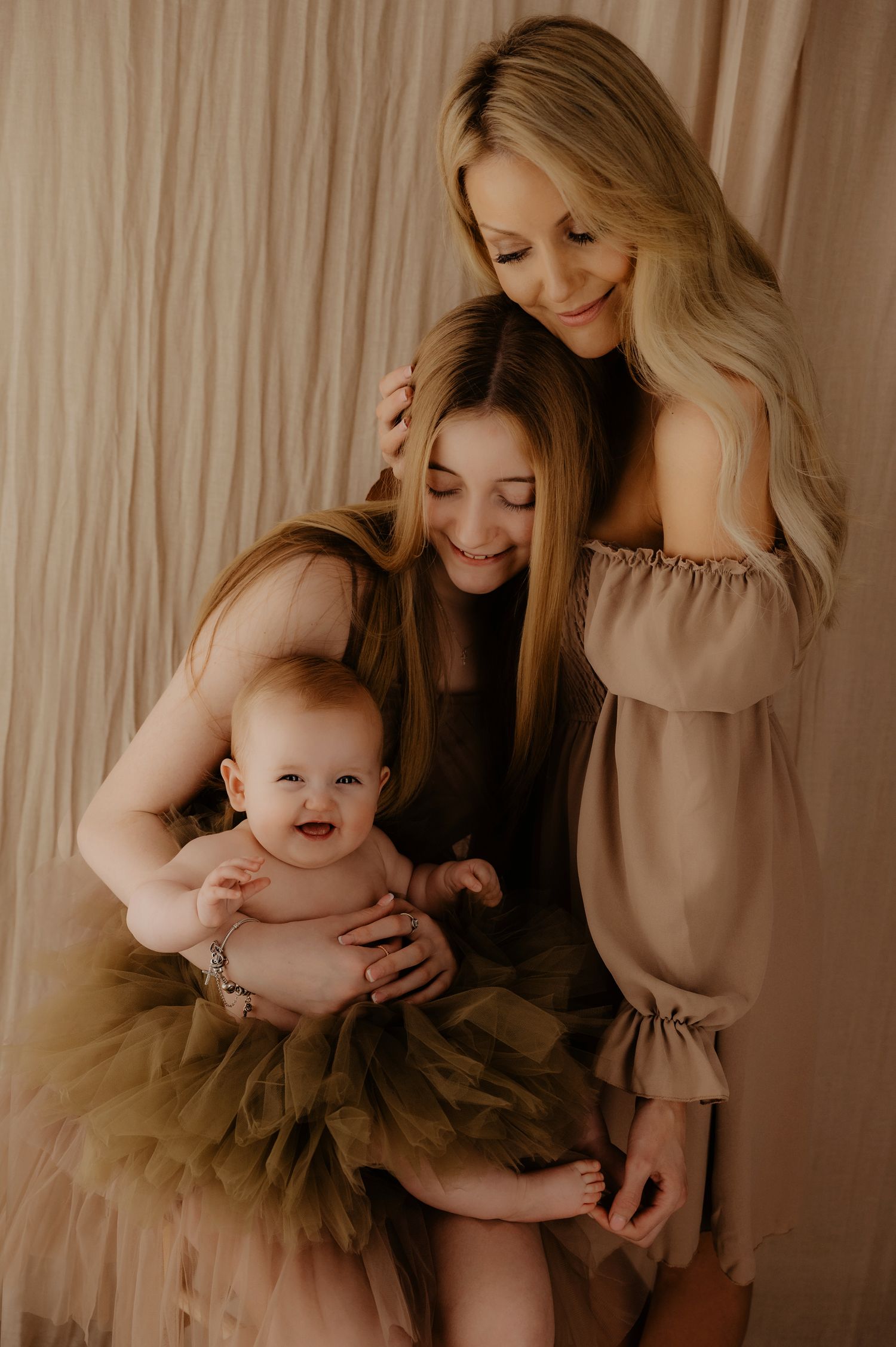 Mother and child bonding in matching beige outfits during cozy studio portrait session.