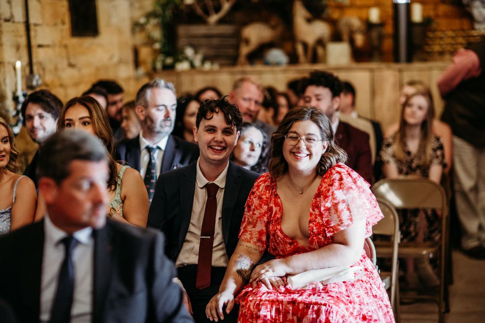 Wedding guests enjoying ceremony in intimate rustic venue with exposed brick walls.