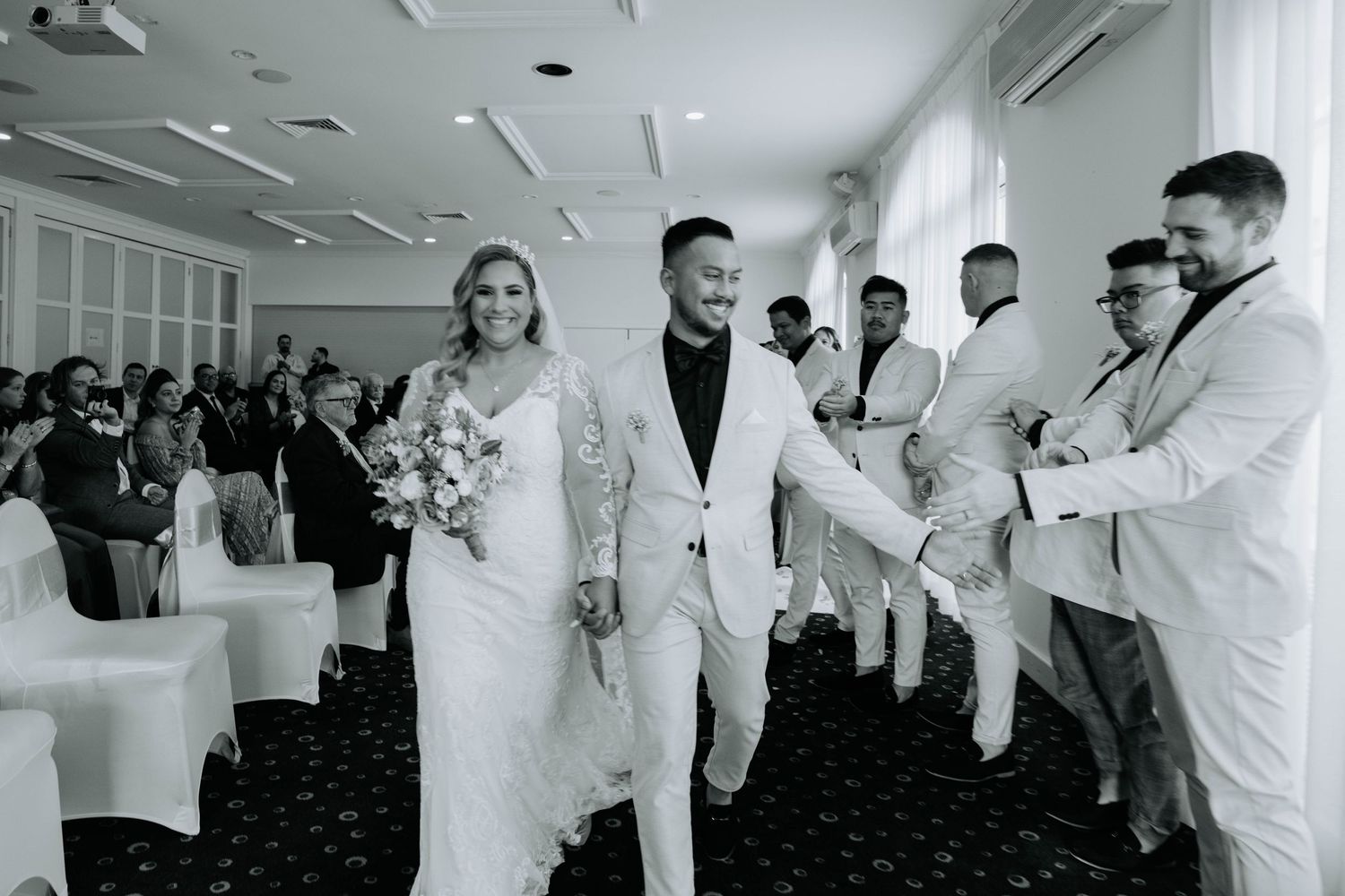 Wedding party making their grand entrance into an elegant reception hall.