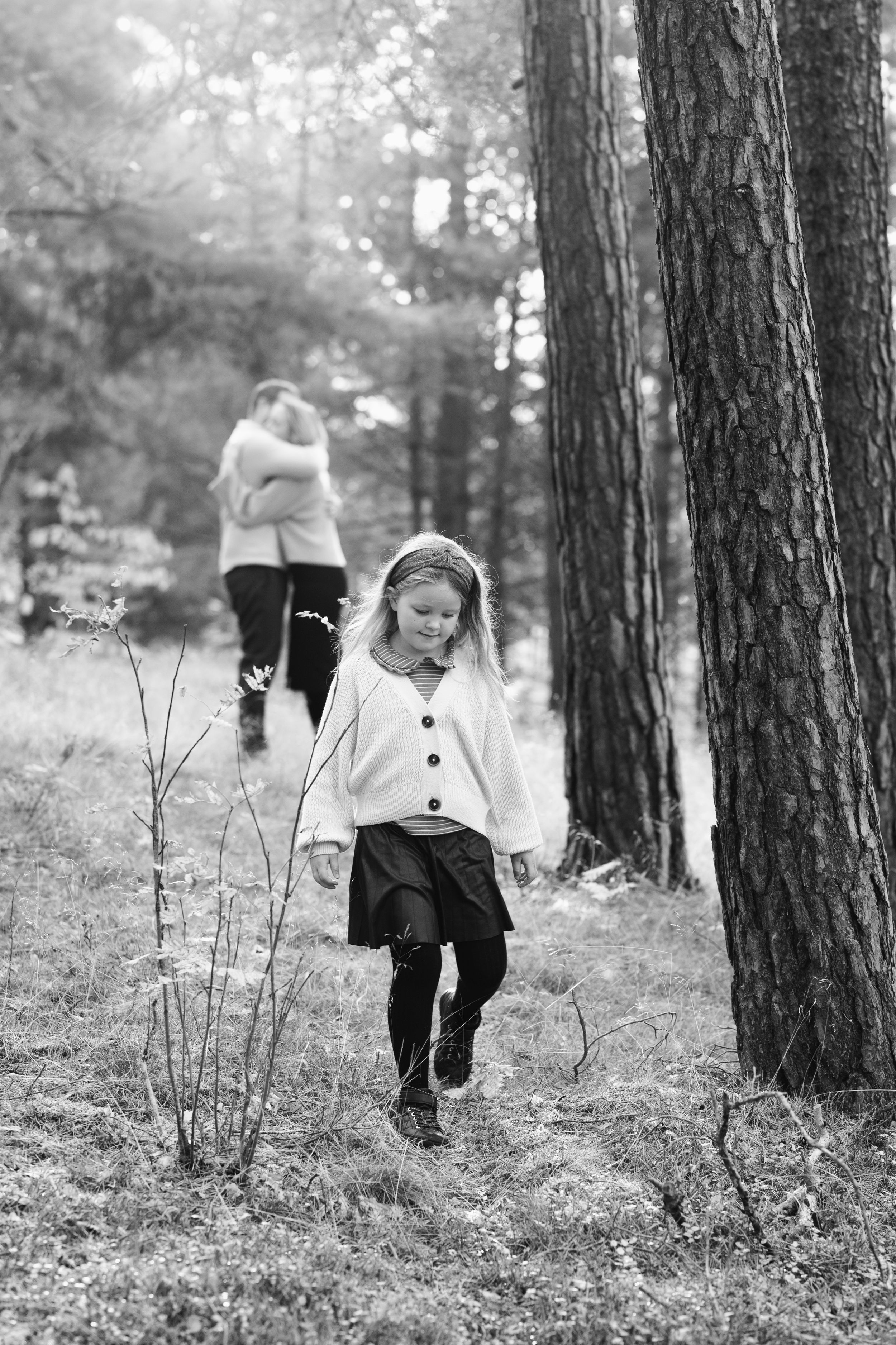 Person walking through a forest path in black and white photography.