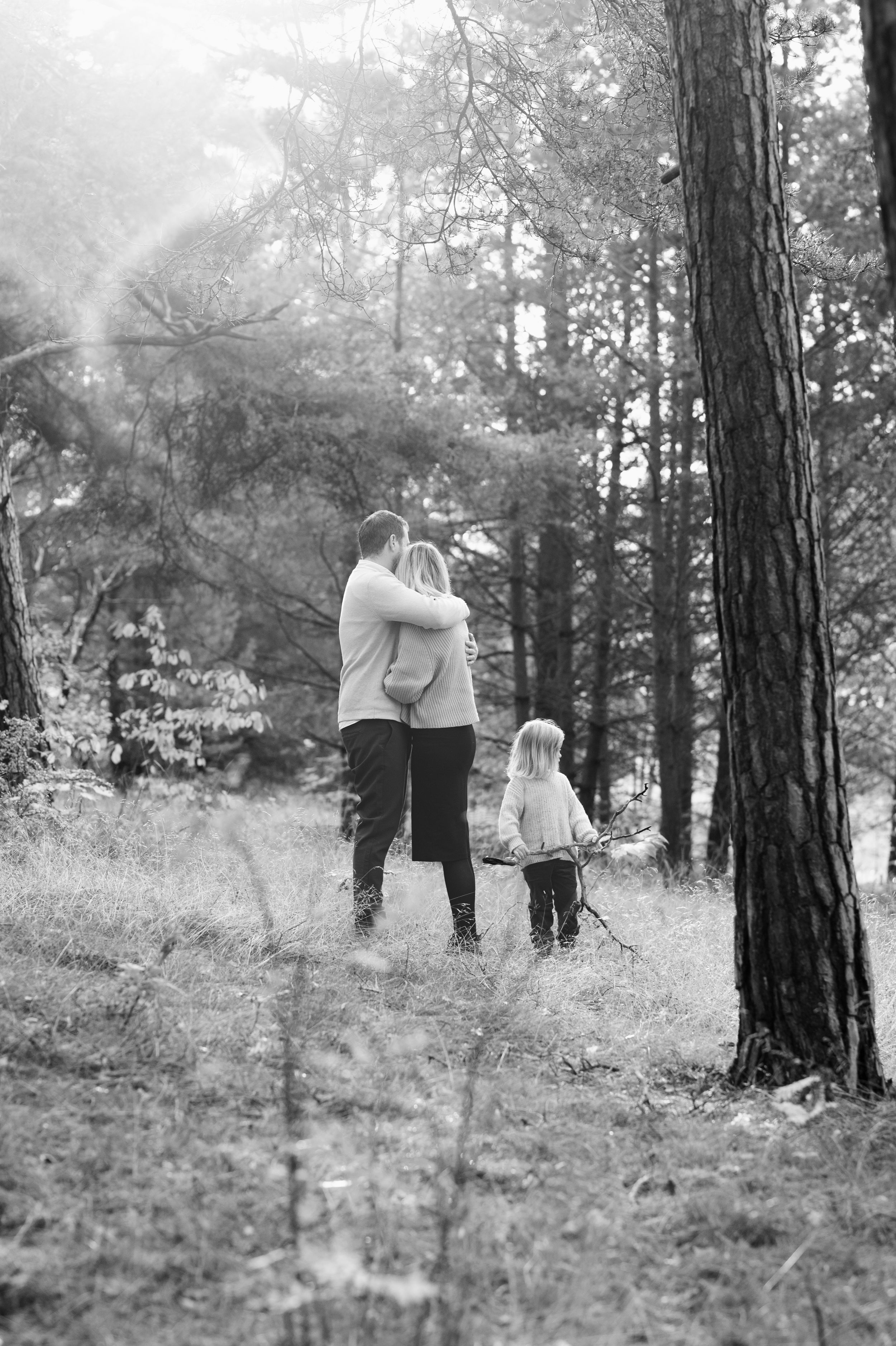 Two people standing together in a misty forest in black and white.