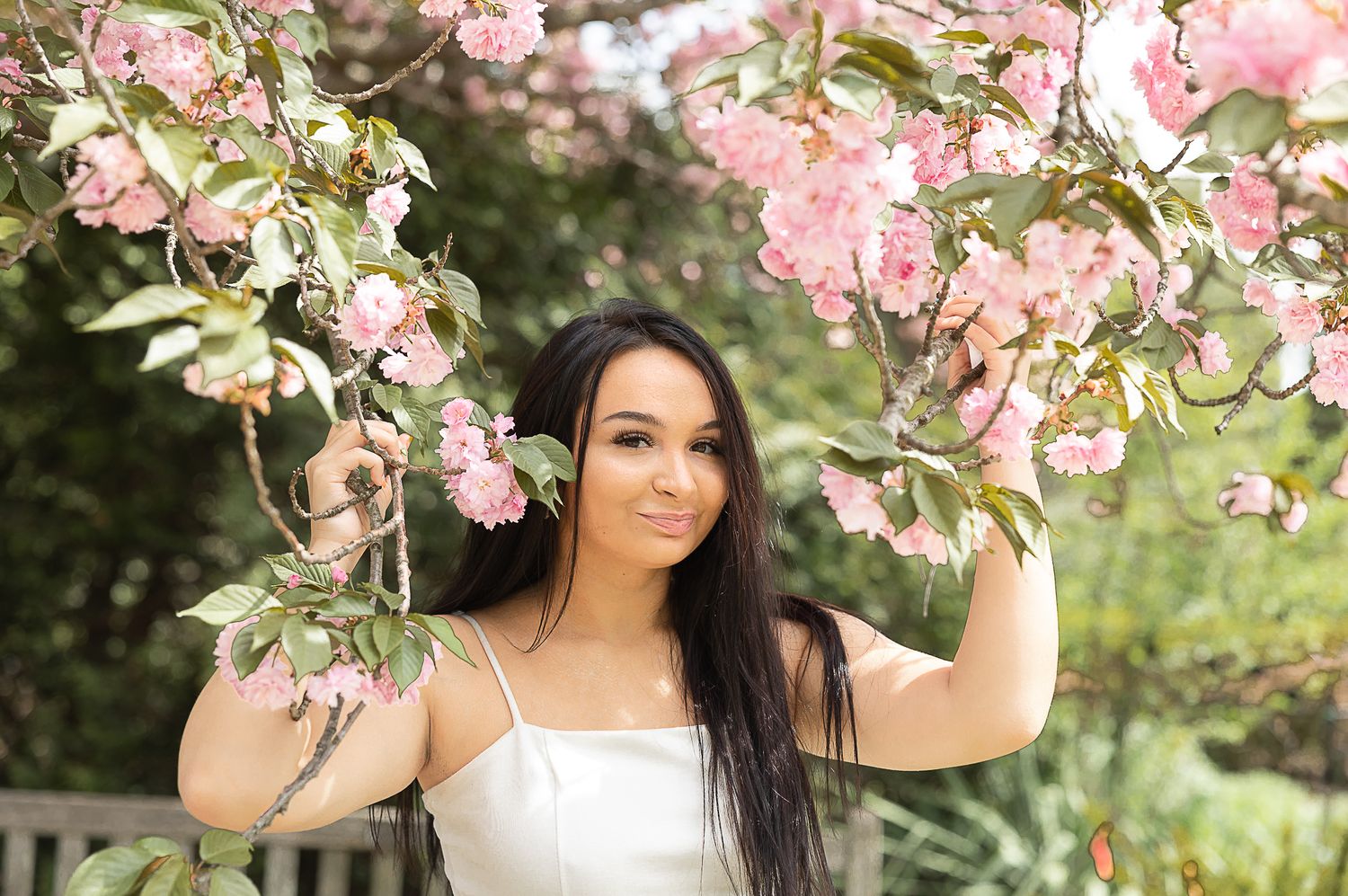 Beautiful spring portrait under pink cherry blossoms with soft natural lighting.