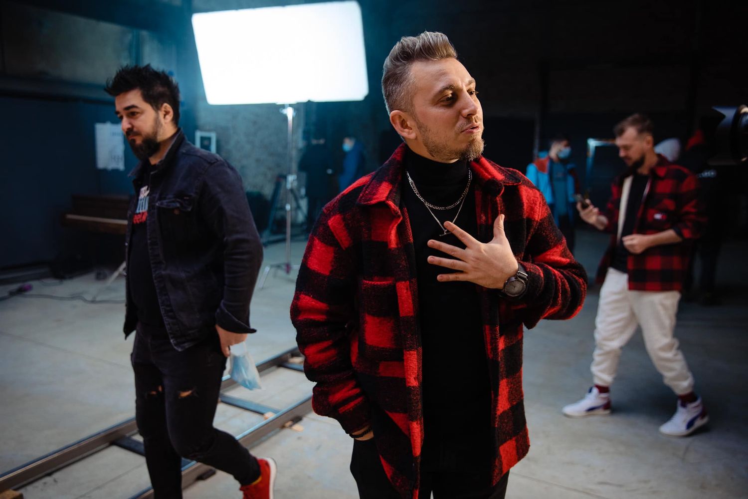People in red and black clothing performing in dark studio space with dramatic lighting.