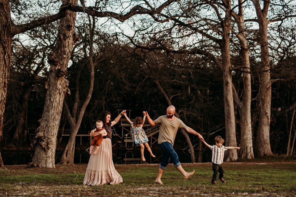 family of five walking by the trees and river