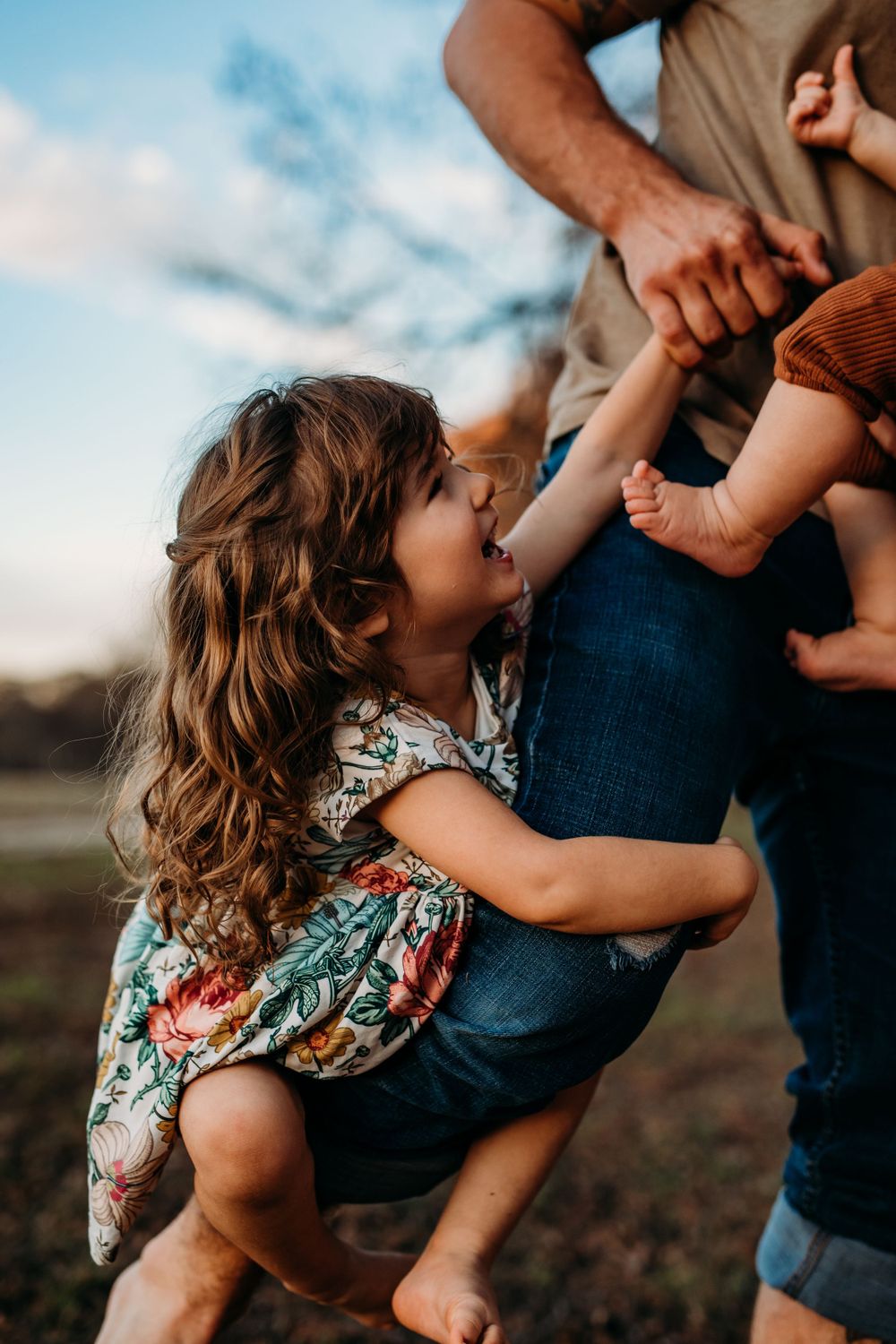 little girl climbing up her dads leg