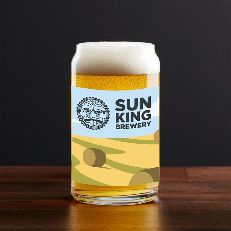 Glass of golden beer with Sun King Brewery logo and desert landscape design.