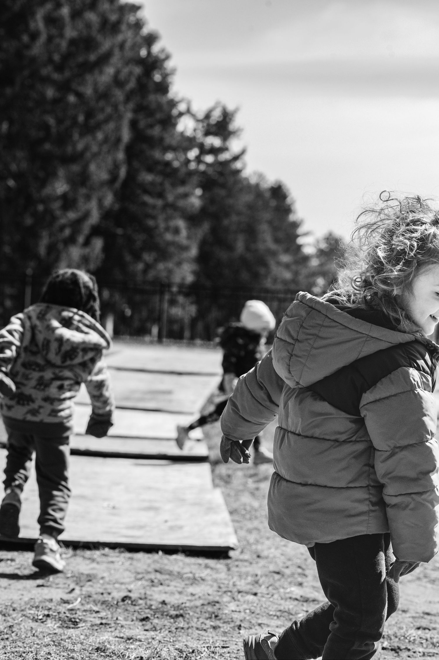 Children playing and running outdoors in winter coats on a blurred background.