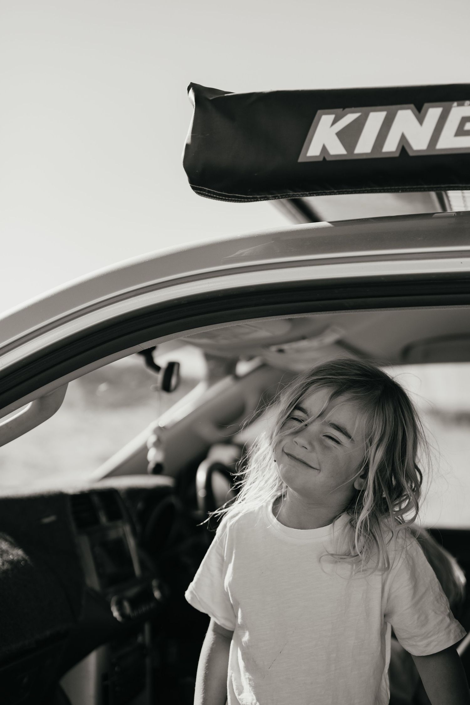 Child smiling in car with Kindi roof rack mounted above.