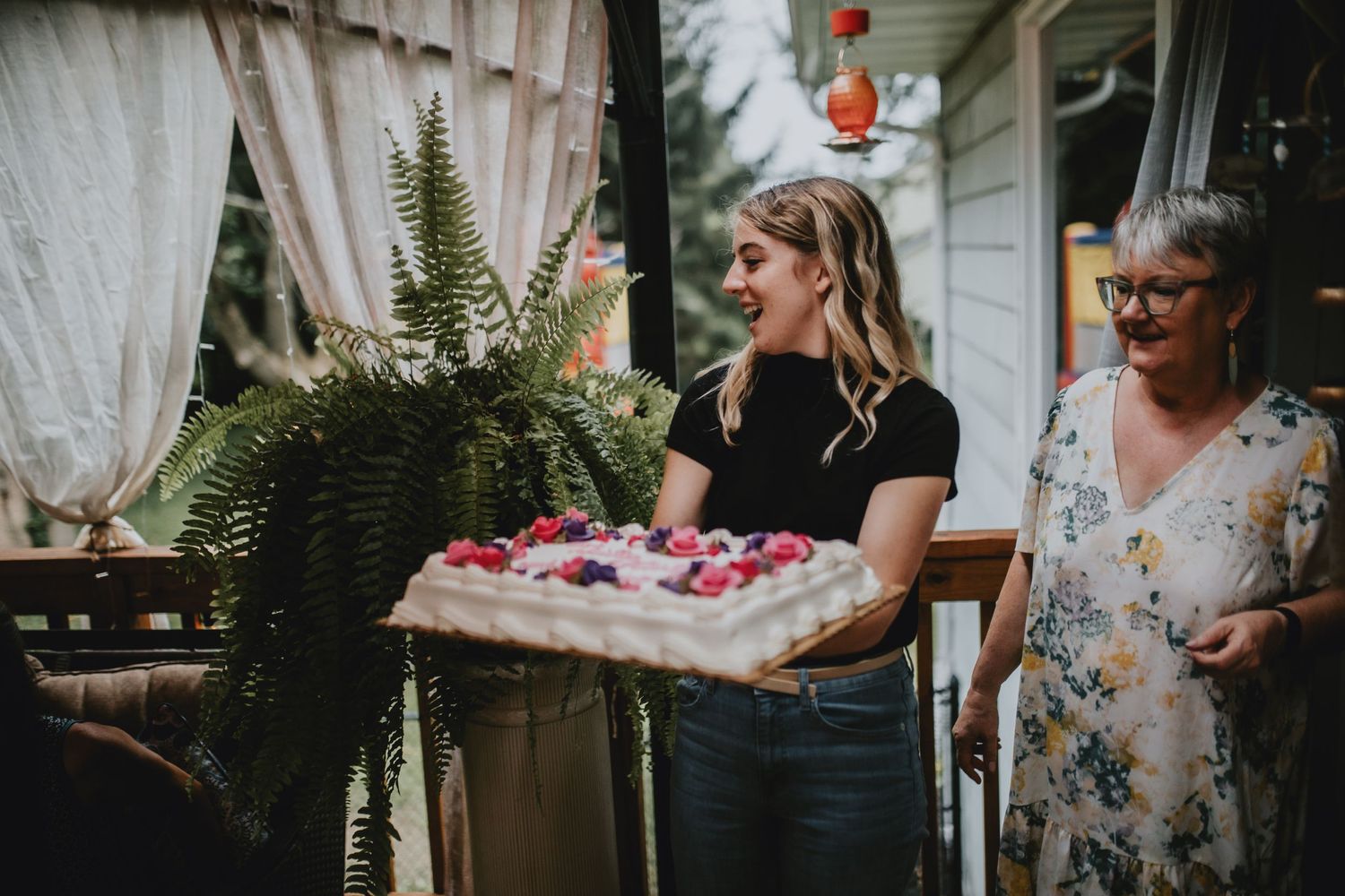 girl in black shirt brining a birthday cake
