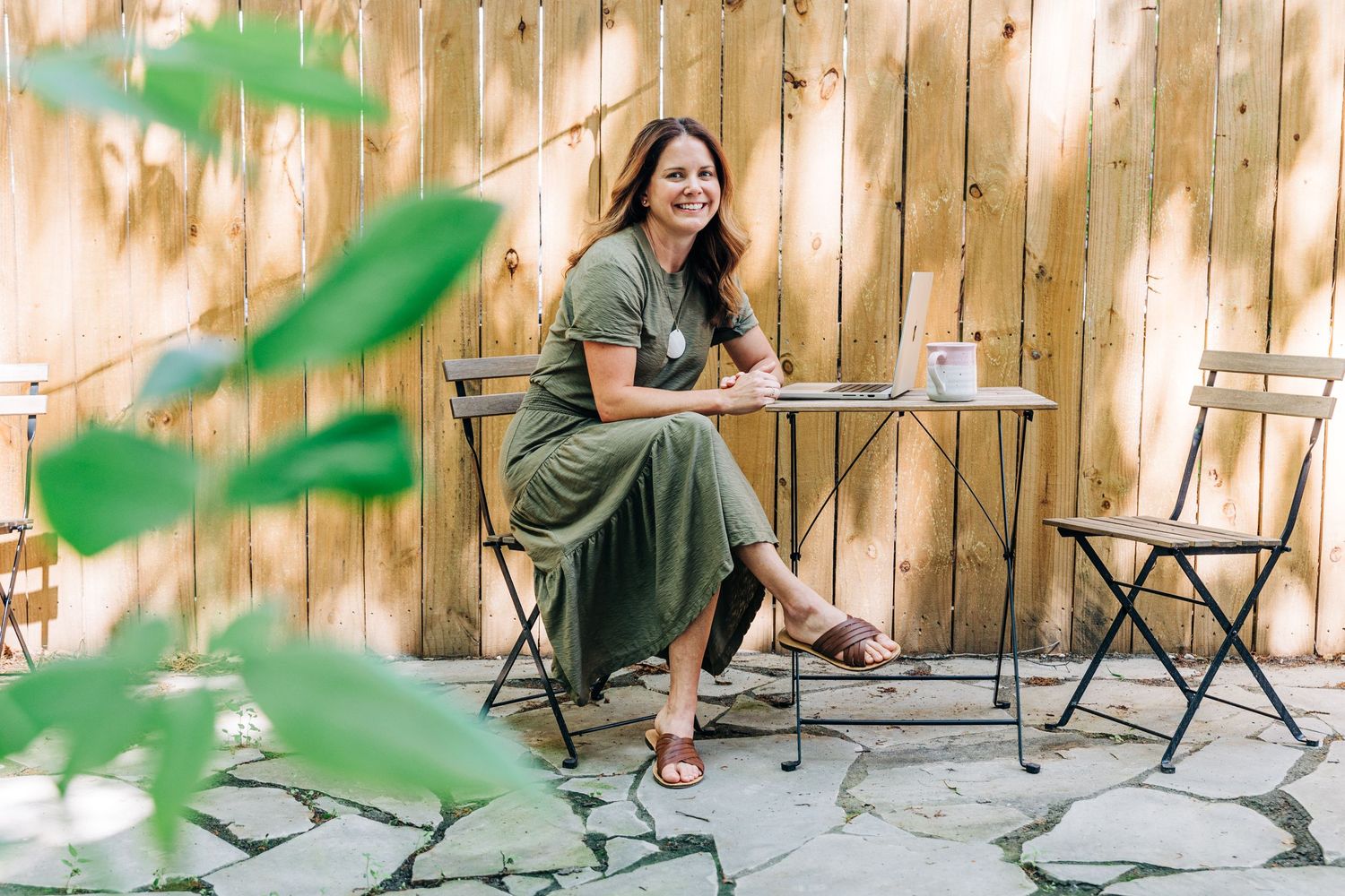 brand photographer sitting outside for her own branding photos with her laptop and coffee at Little Villa Charlotte