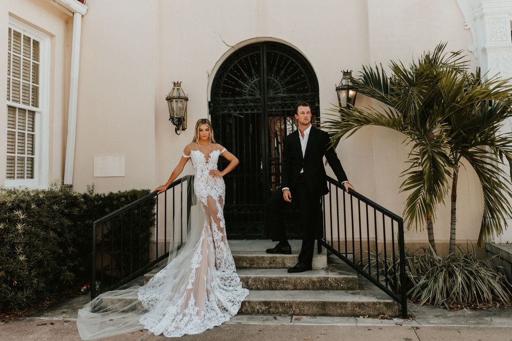 Elegant wedding portrait on cream colored building steps with ornate black door.