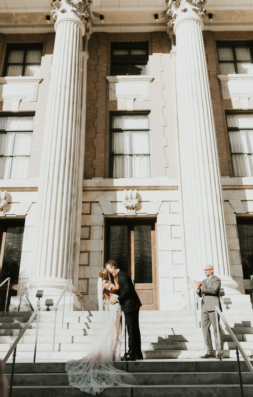 A wedding moment captured between classic white columns at a historic building entrance.