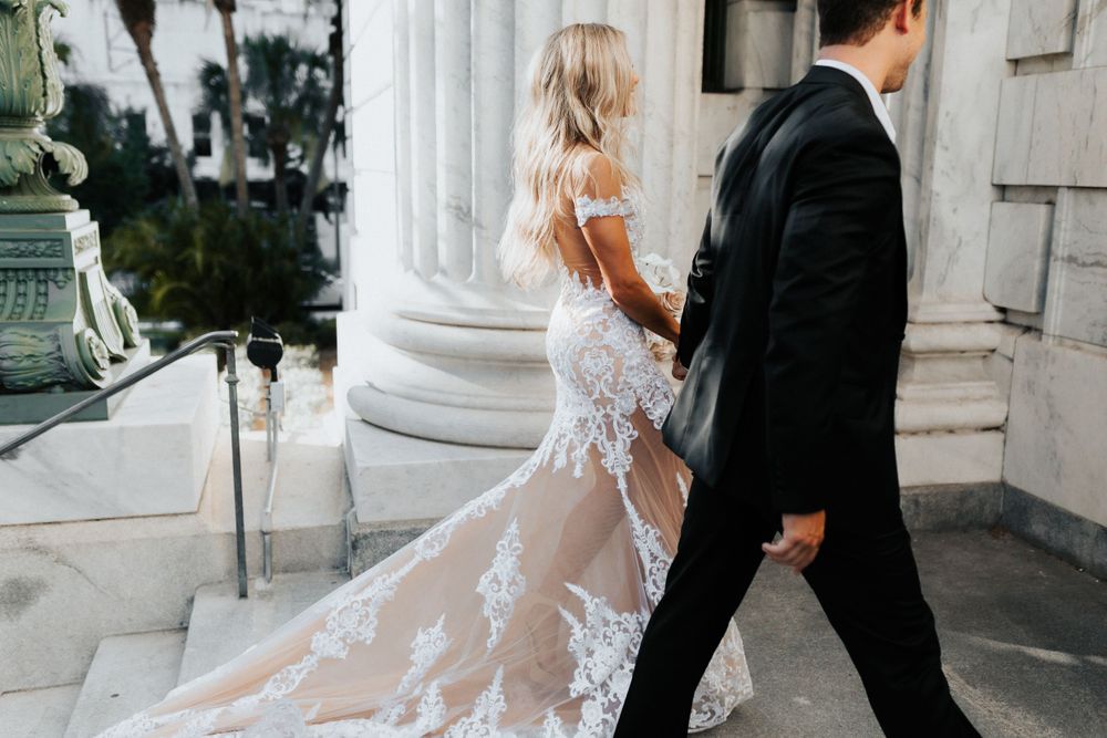 Lace wedding dress with sheer details and train photographed against white columns.