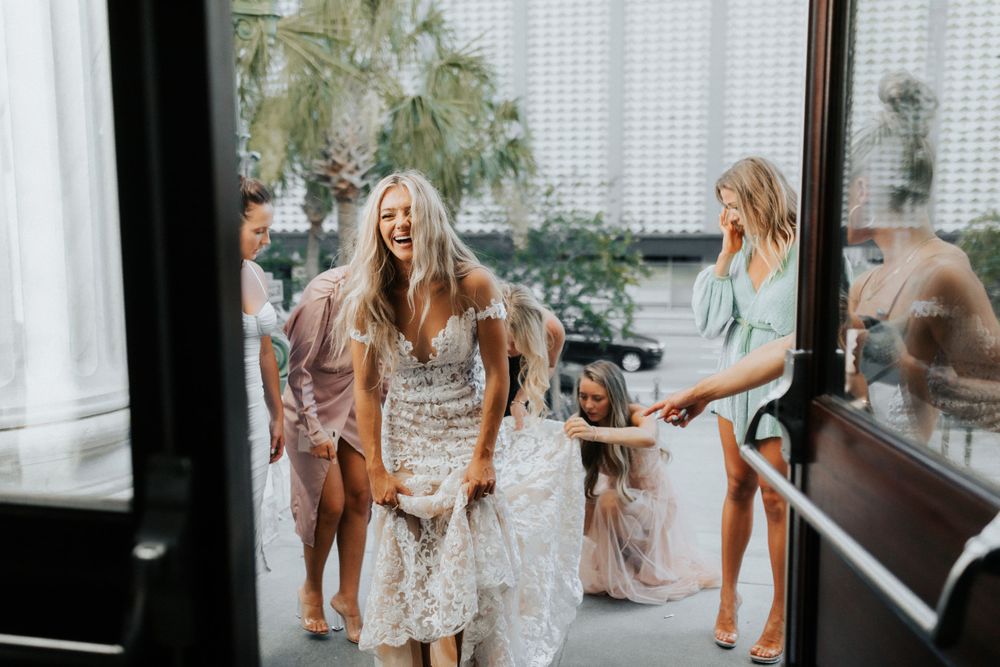 Wedding party gathering indoors near glass doors and white curtains.