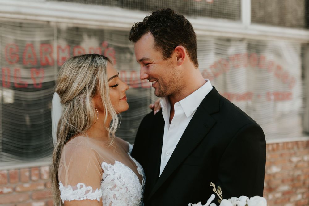 Intimate wedding moment captured against vintage storefront window.