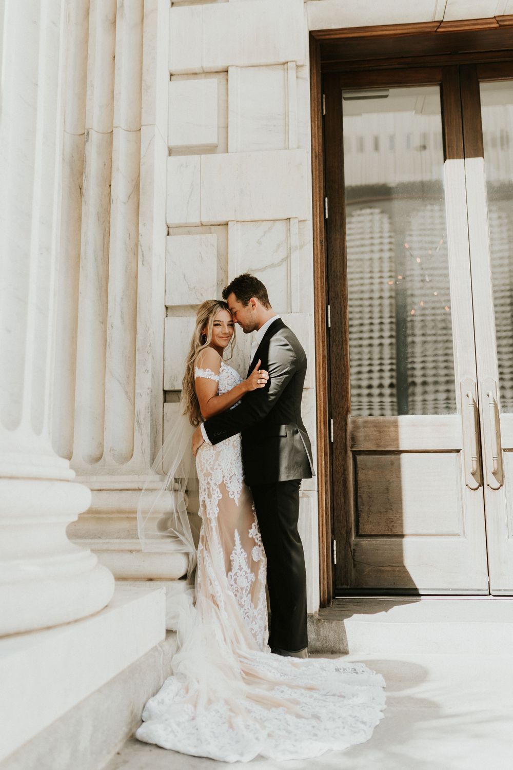 Romantic wedding photo against classic white columns and architectural details.