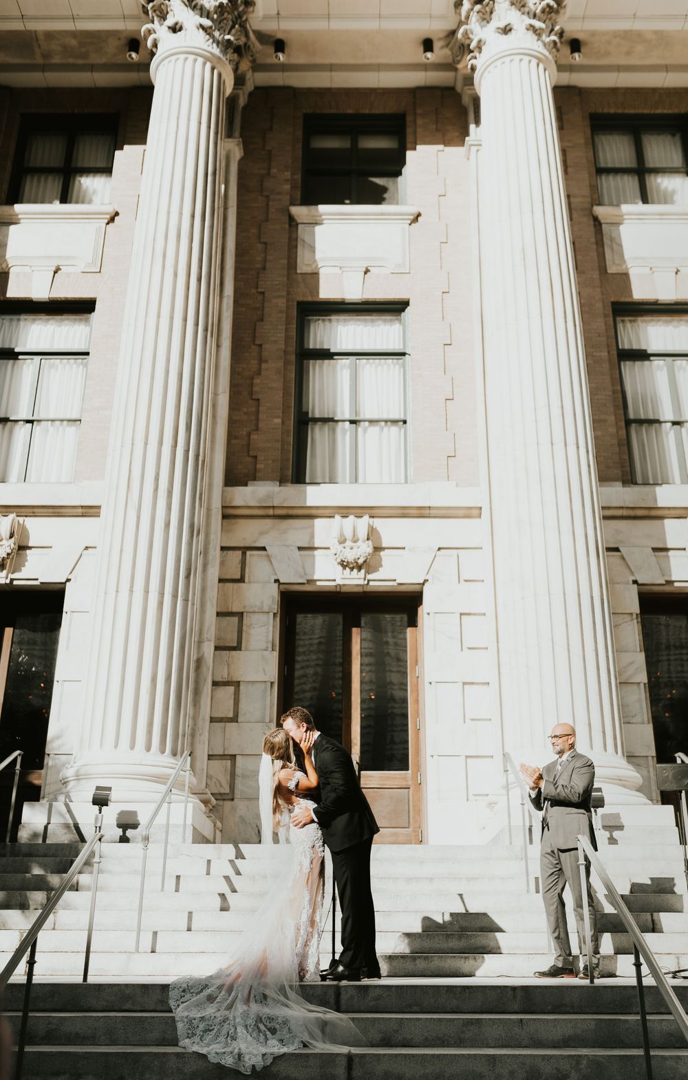 Wedding ceremony on grand stone steps with classical columns in background.