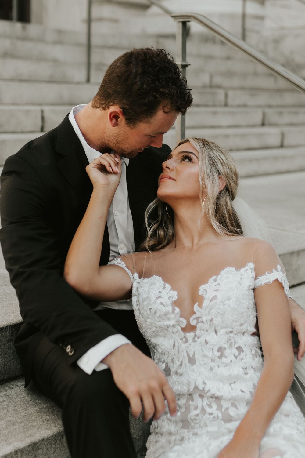 Romantic wedding couple sharing an intimate moment on stone steps.