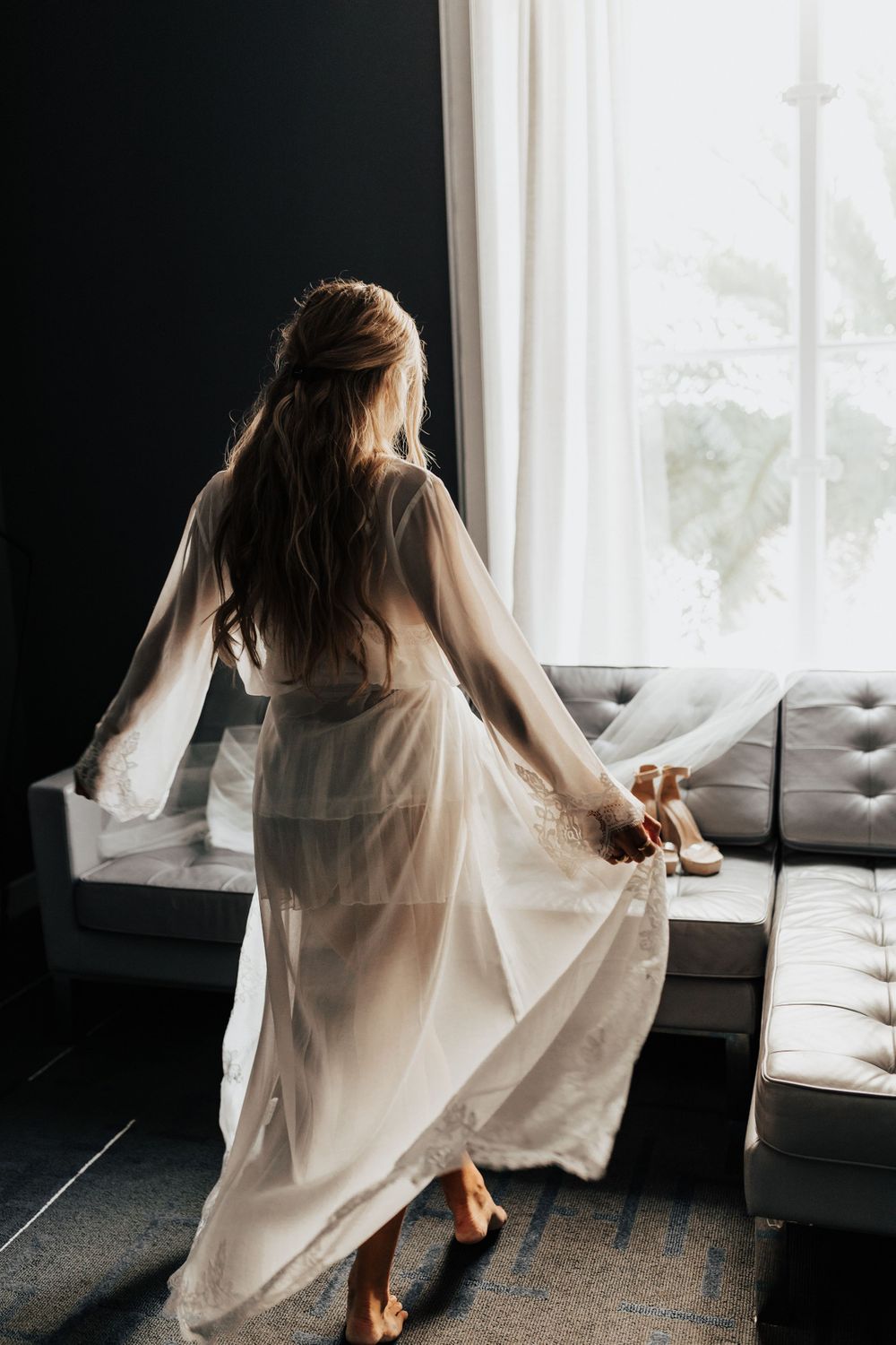 Flowing white sheer robe captured in motion against bright window and modern furniture.