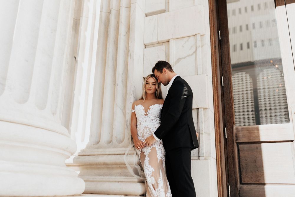 Intimate wedding moment captured between couple by classical white columns.