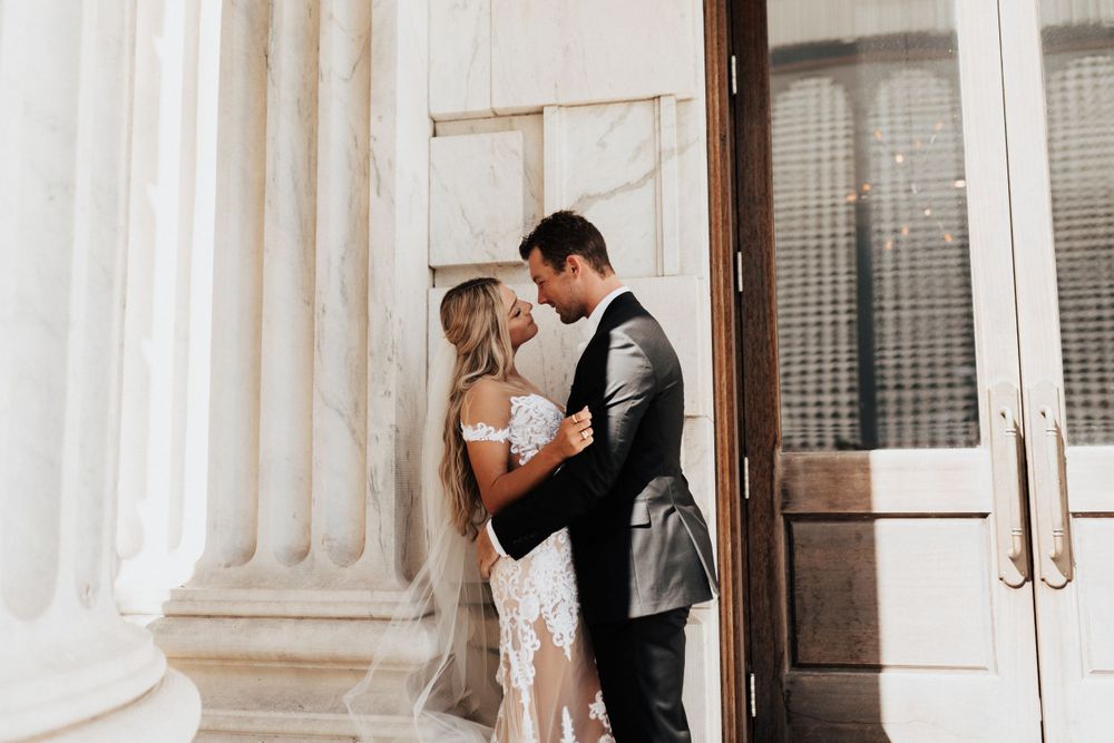 Intimate moment between newlyweds captured against classic architectural backdrop.