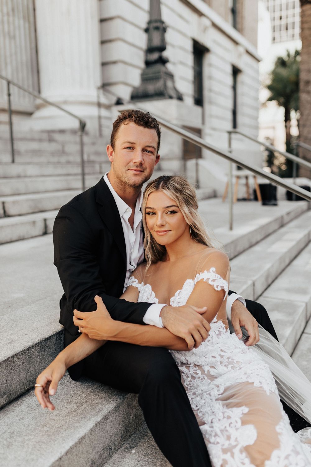 A romantic wedding photo on stone steps featuring an intimate moment between newlyweds.