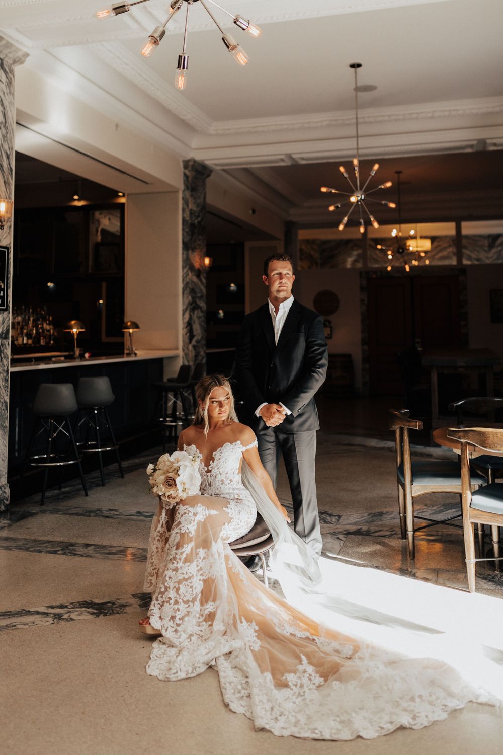 A elegant wedding scene in a modern venue with a stunning white lace gown with long train.