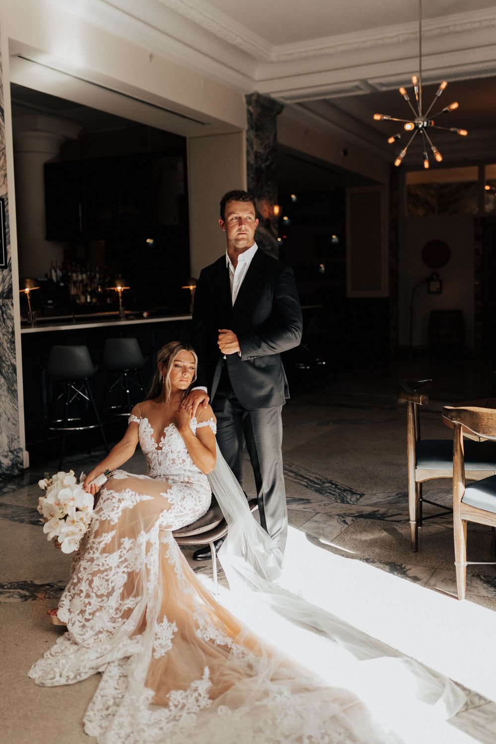 An intimate wedding portrait in a modern venue with dramatic lighting and elegant decor.