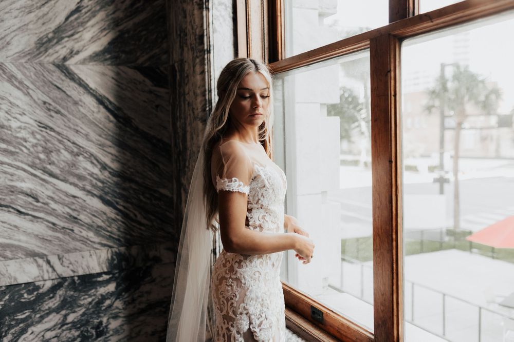 An intricate lace wedding gown with sheer details captured in natural window light.