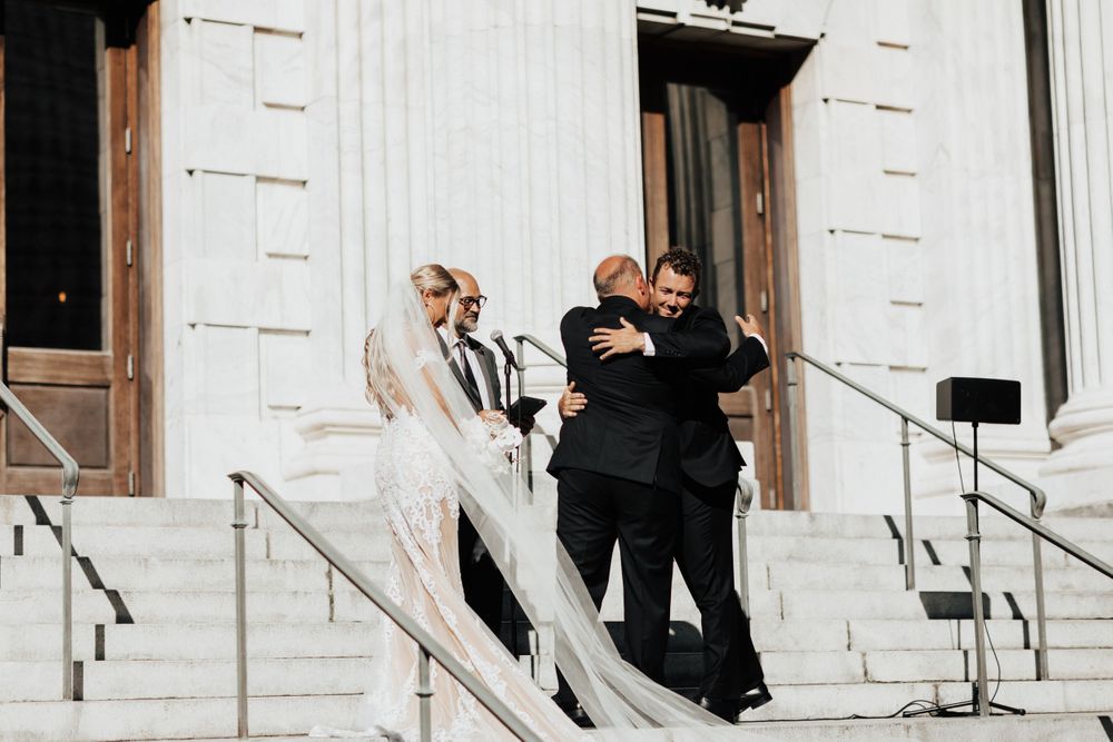 Wedding ceremony on grand stone steps of classic building.