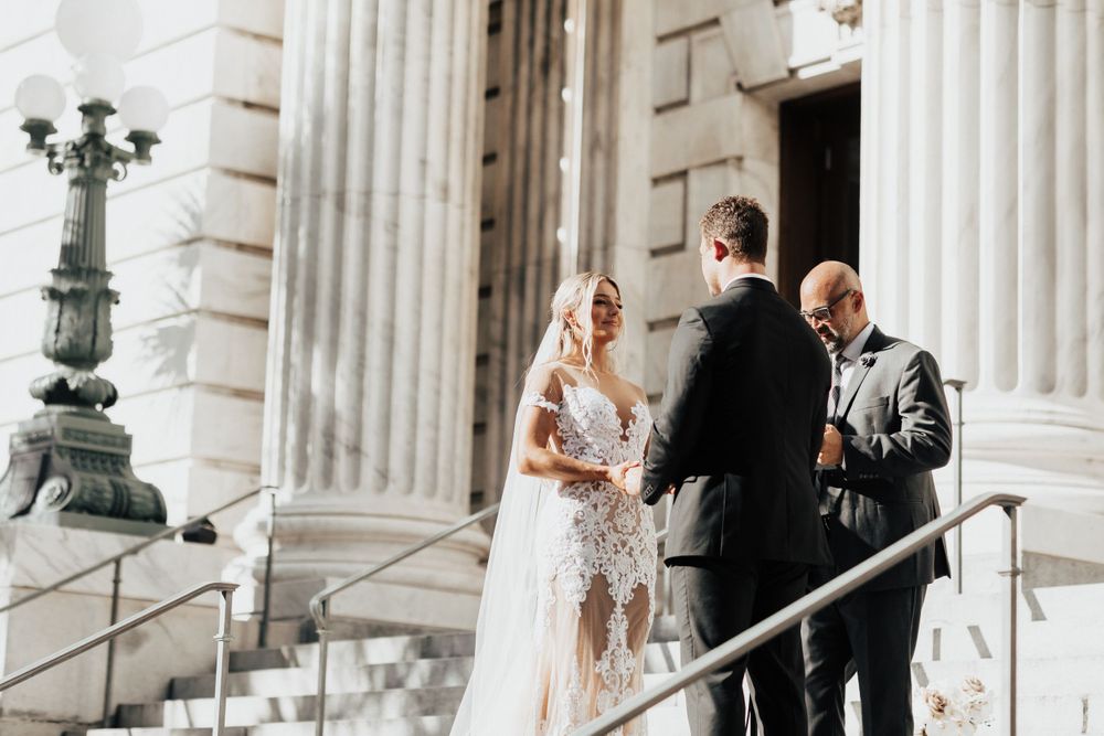 Wedding ceremony moment on steps of classical building with white columns.